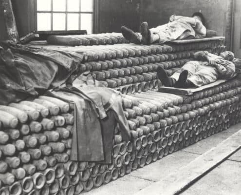Slapende arbeiders der Artillerie Inrichtingen op stapel granaatbussen